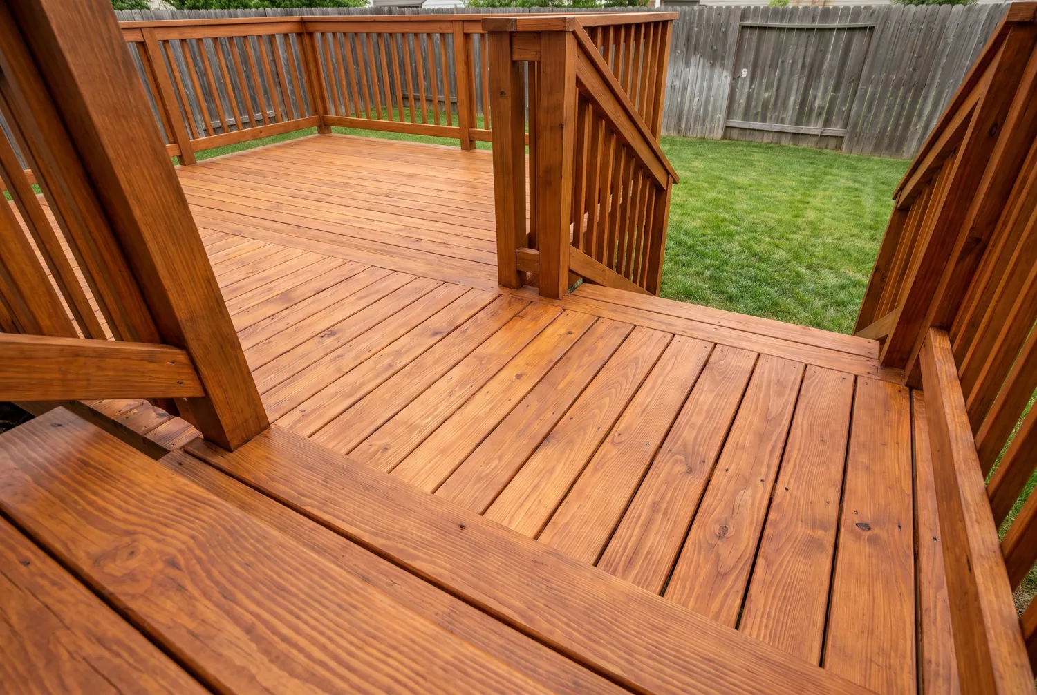 The same deck after staining, in a rich warm cedar tone with the grain showing