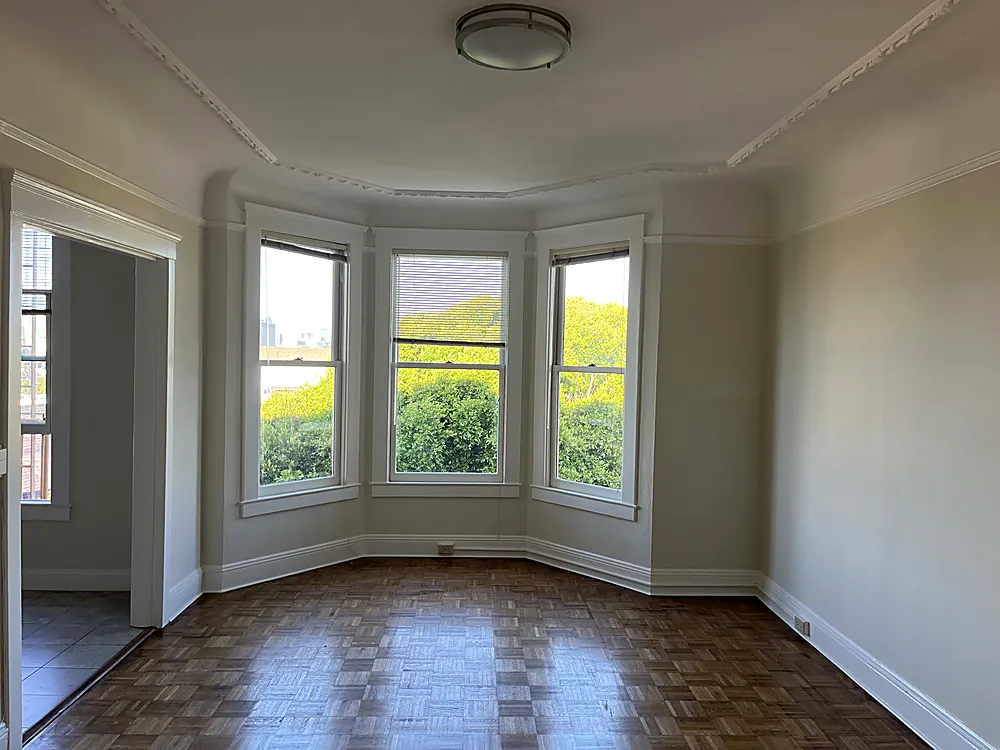 A living room with a curved bay window, freshly painted walls and white trim