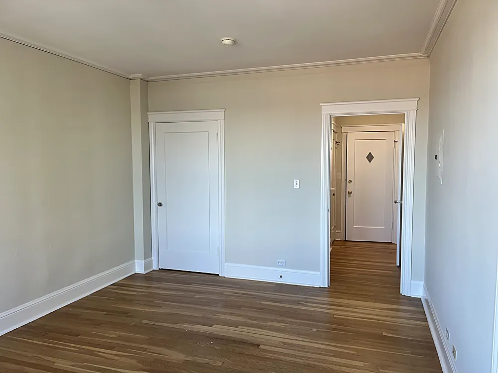 An empty room painted a warm neutral with crisp white baseboards and casing