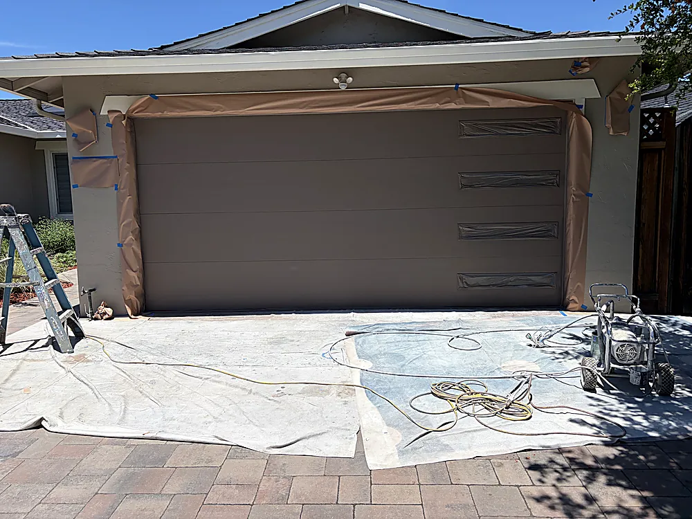 The same garage door after its finish coat with the sprayer on the driveway