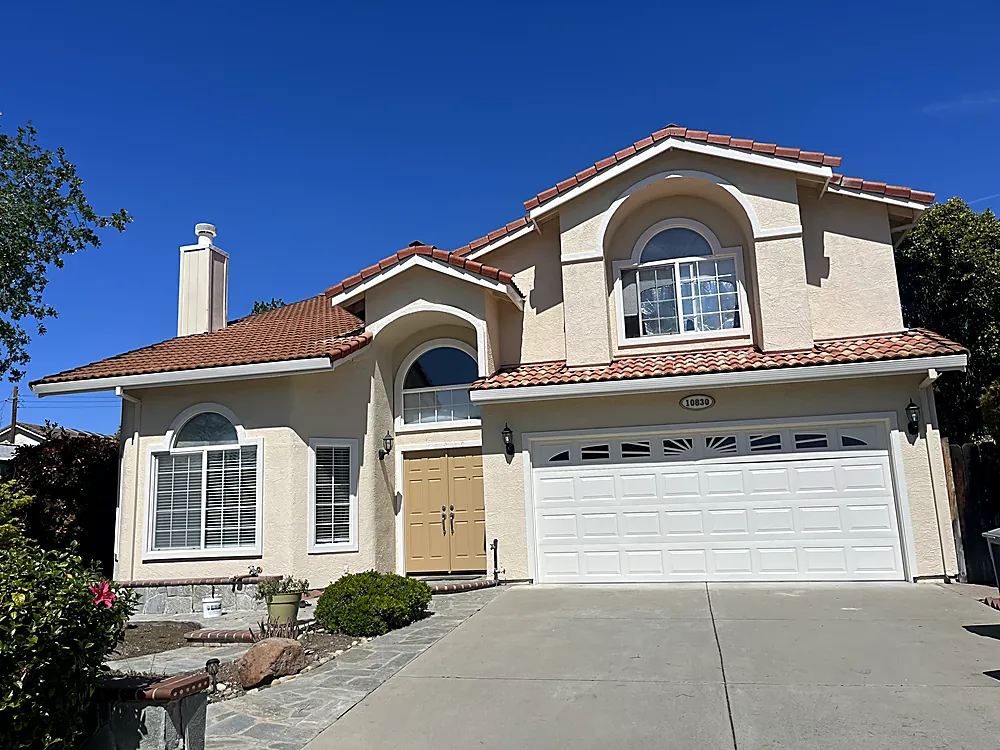A stucco home with an arched entry, freshly painted in warm cream