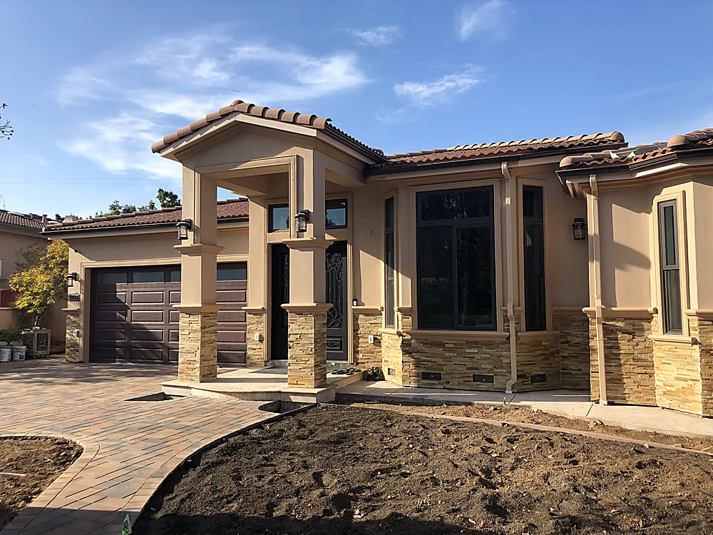 A large Mediterranean style stucco home with stone accents and a tile roof