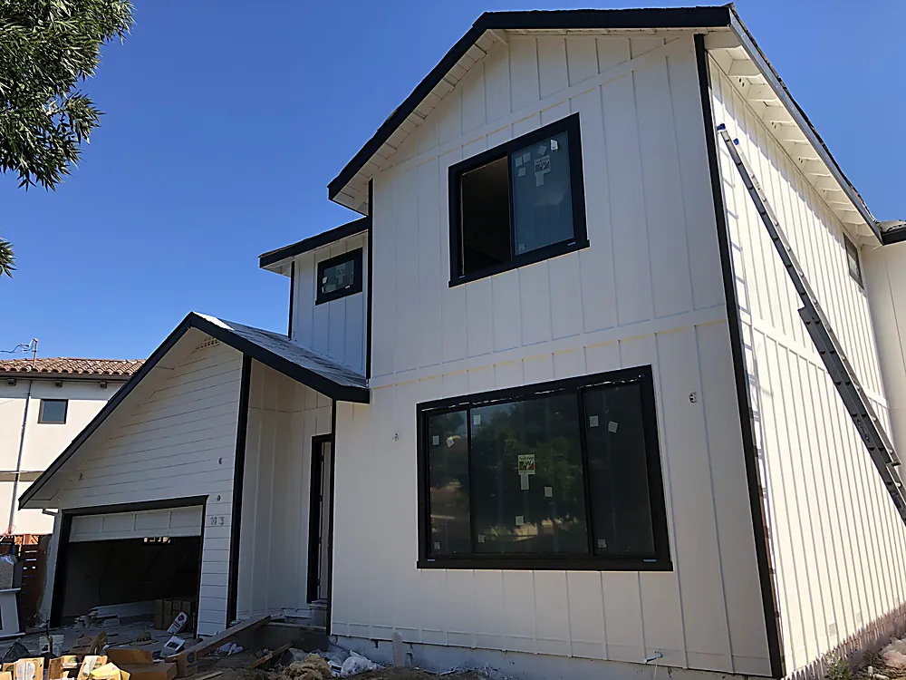 A newly built home in white board and batten siding with black window trim