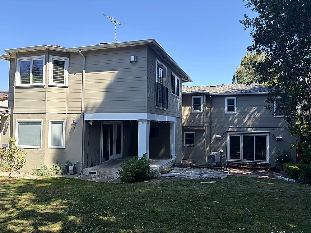 The rear elevation of a two story home repainted in taupe with white trim