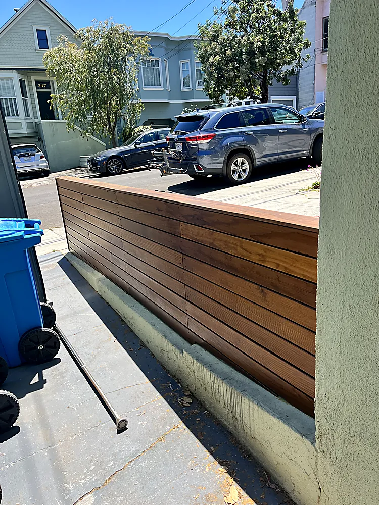 A horizontal wood slat fence stained a warm natural tone