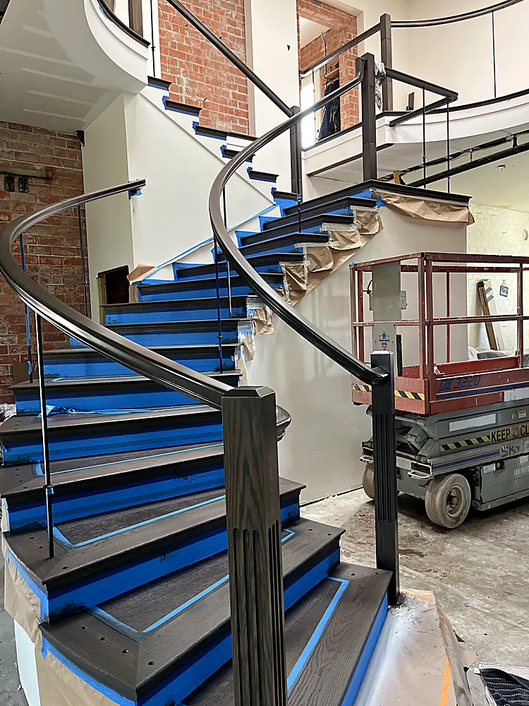 A curved interior staircase fully masked in blue tape with a lift in the room