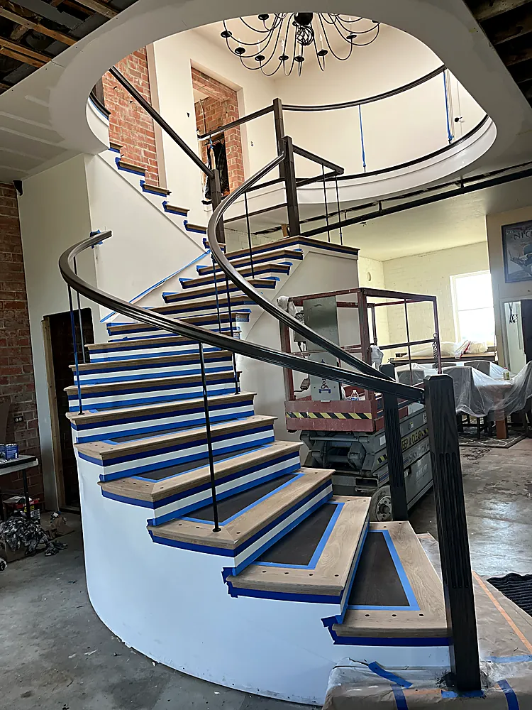 The same curved staircase masked in blue tape seen from below