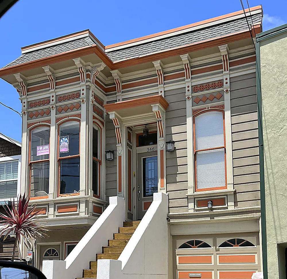 A grey Victorian with ornate trim detailed in terracotta and cream