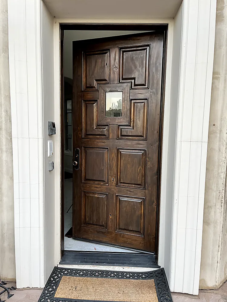 A panelled wood front door refinished in a deep natural stain