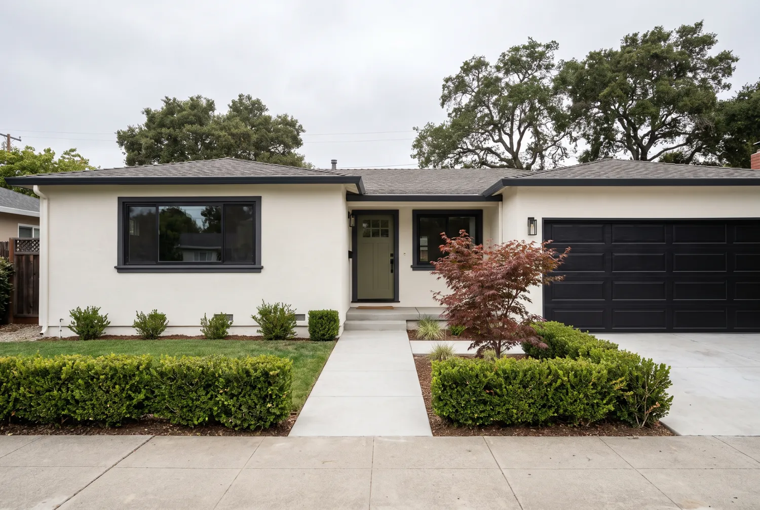 The same home after painting, with crisp off white stucco and charcoal trim